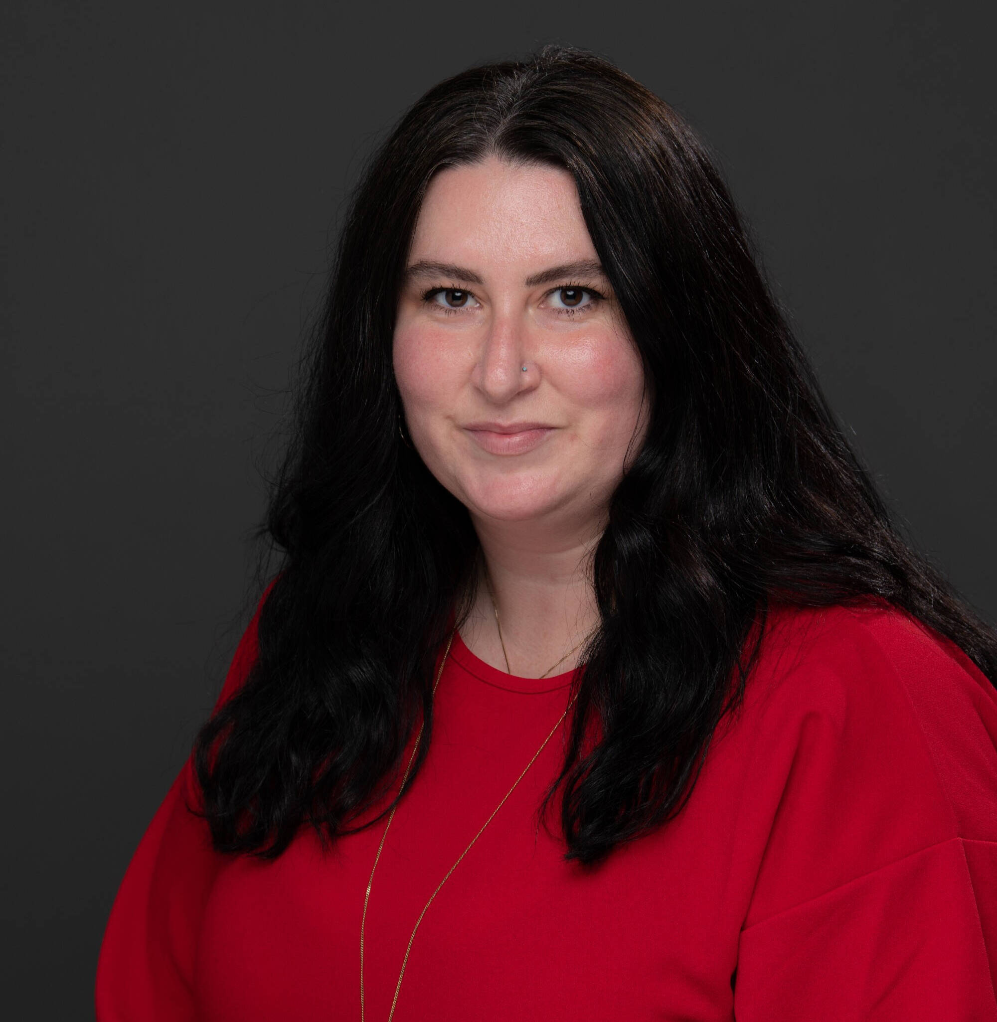 Allison Bazaire in a red blouse on a dark background